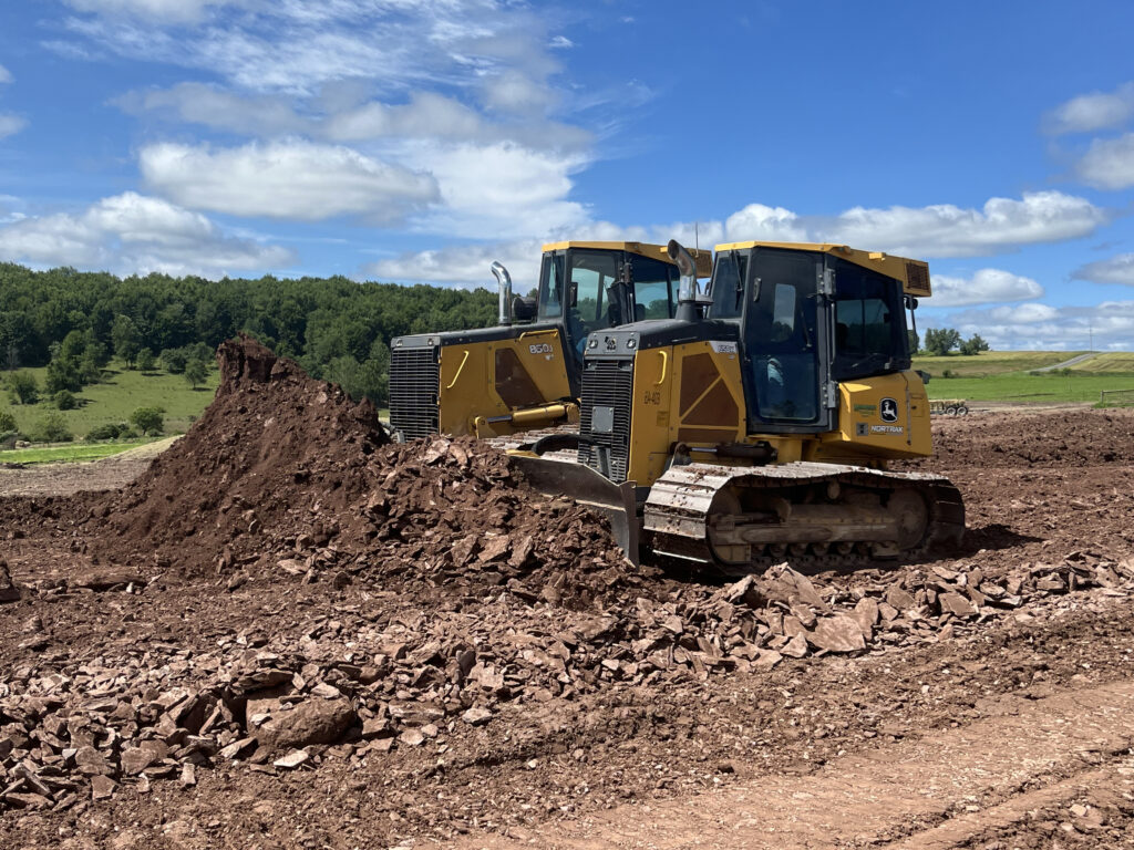 Two bulldozers pushing dirt on a construction site