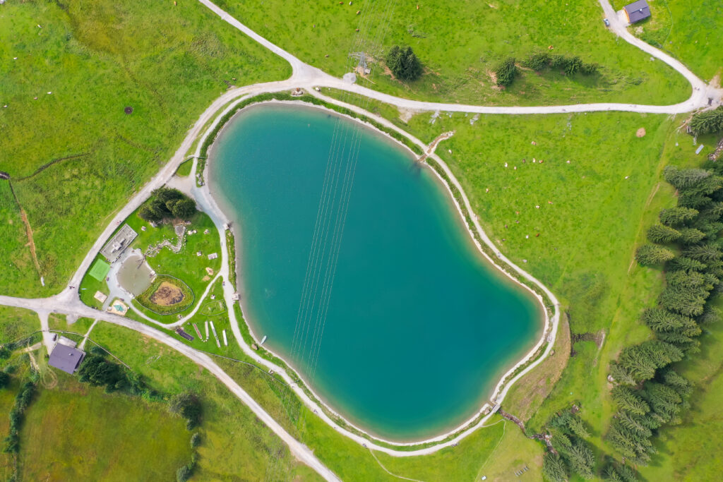 Aerial view of large pond surrounded by green landscape and access roads