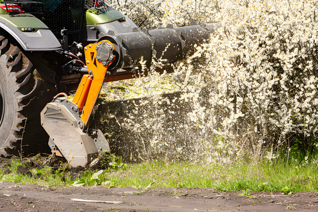Forestry mulcher attachment clearing brush and vegetation along roadside